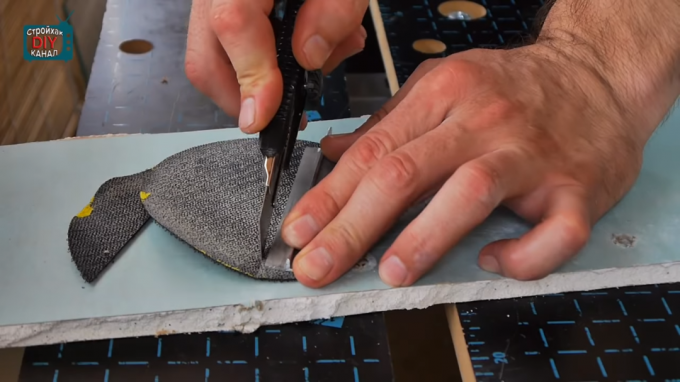 सर्कल से sanding के कपड़ा काटने को अपने हाथों के साथ संलग्नक बनाने के लिए करने की प्रक्रिया